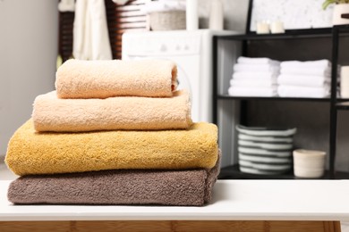 Photo of Stack of clean towels on white table in laundry room, space for text