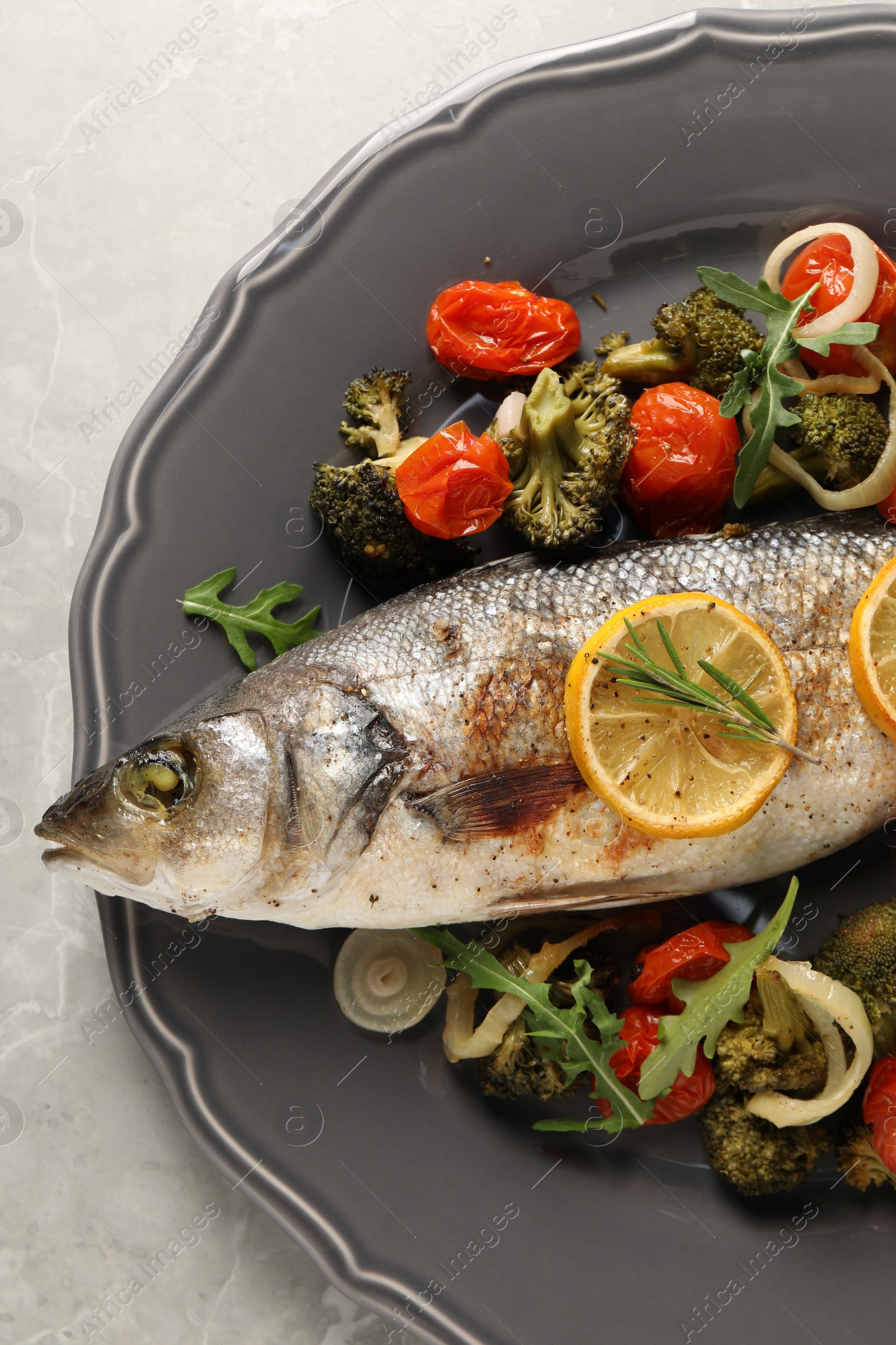 Photo of Baked fish with vegetables, rosemary and lemon on grey textured table, top view