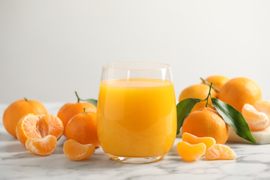 Photo of Glass of fresh tangerine juice and fruits on marble table