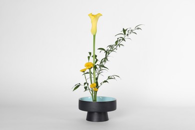 Beautiful ikebana for stylish house decor. Floral composition with fresh calla, chrysanthemum flowers and branches on white background