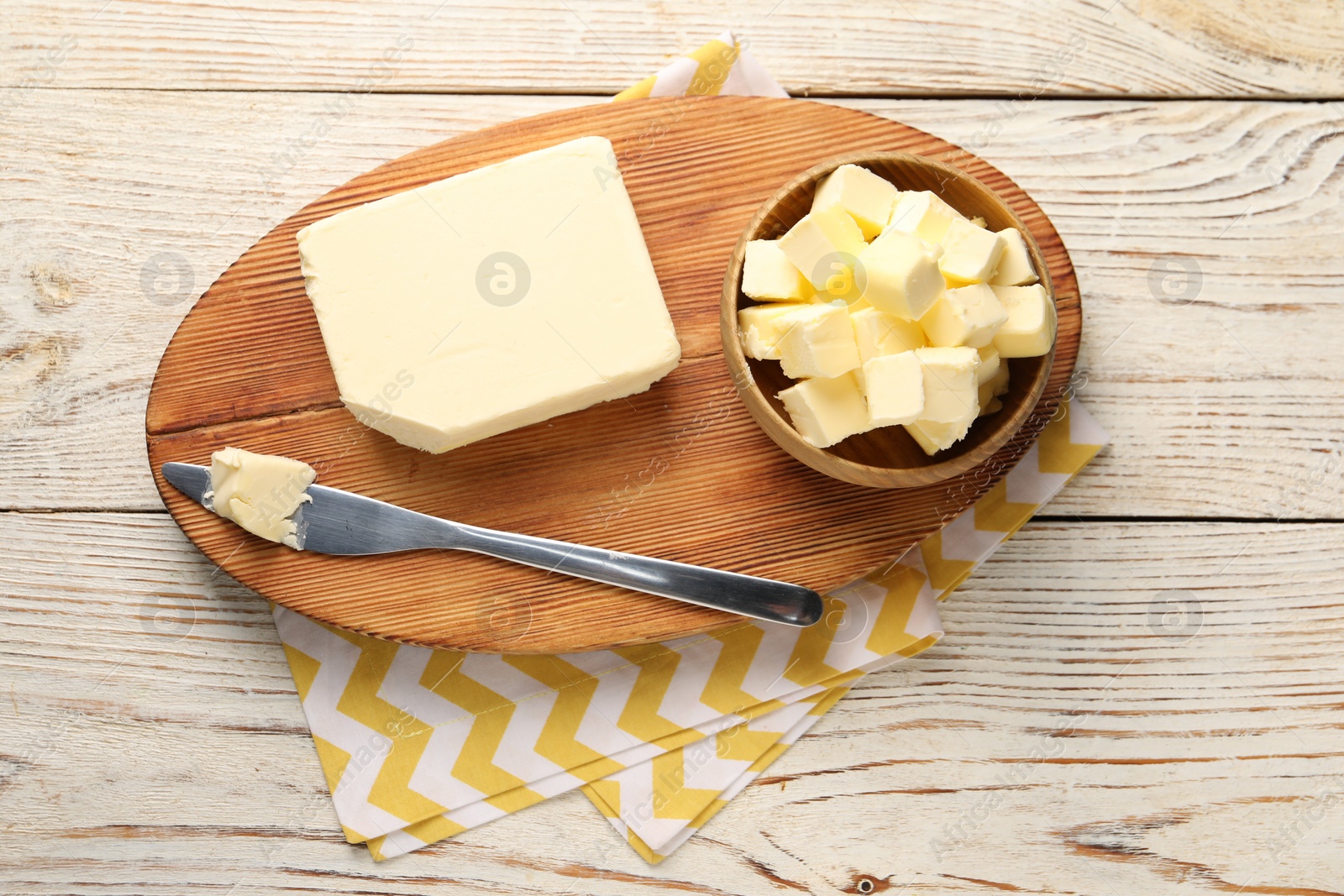 Photo of Tasty butter and knife on light wooden table, top view