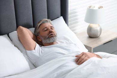 Photo of Man snoring while sleeping in bed at home