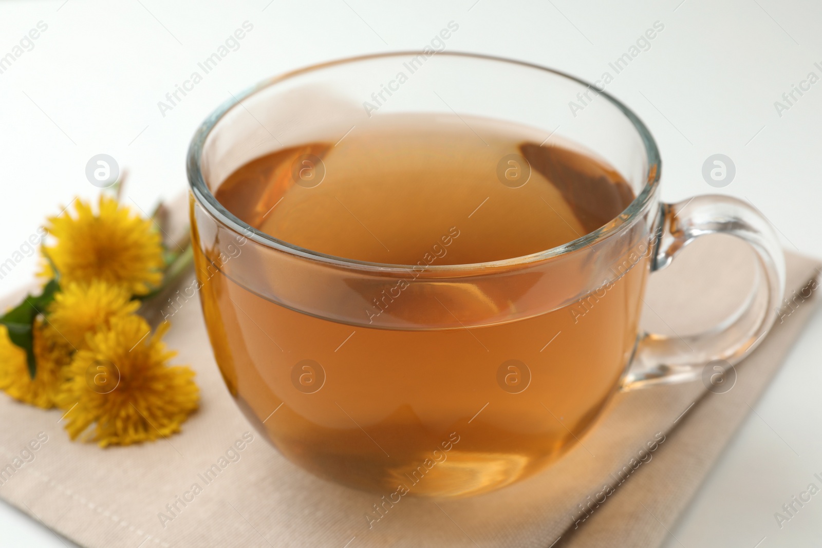 Photo of Delicious fresh tea and dandelion flowers on white table, closeup