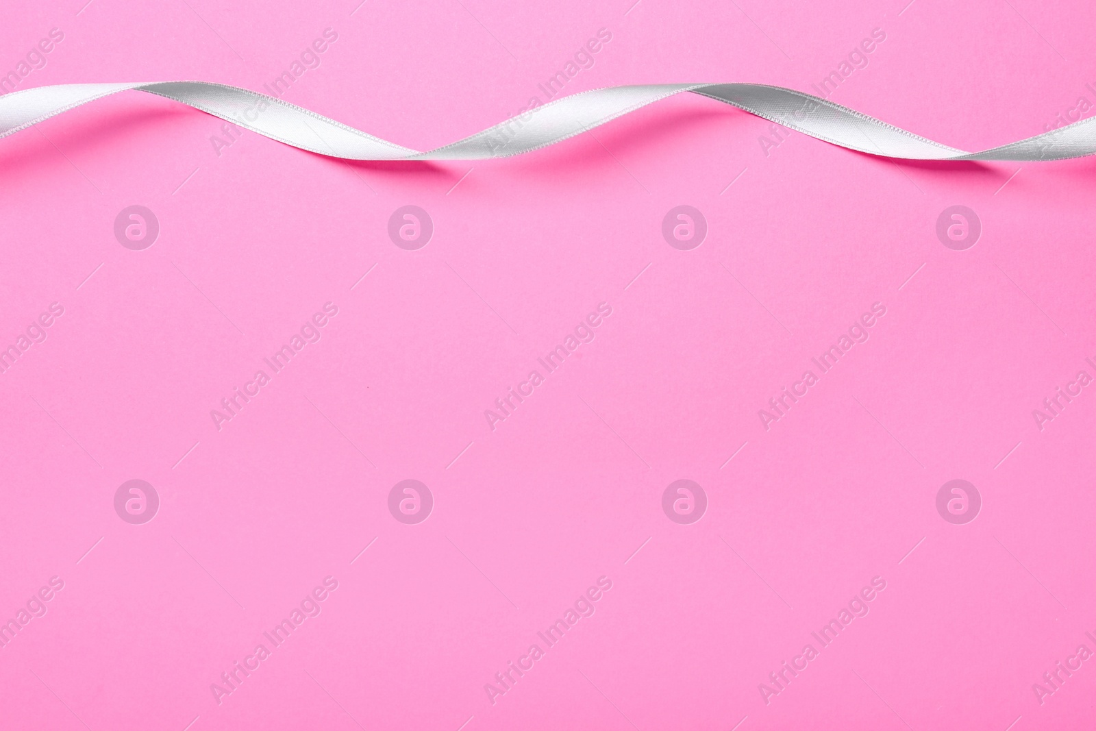 Photo of Beautiful ribbon on pink background, top view. Space for text