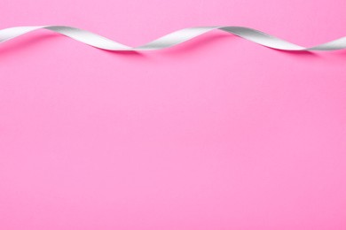 Beautiful ribbon on pink background, top view. Space for text