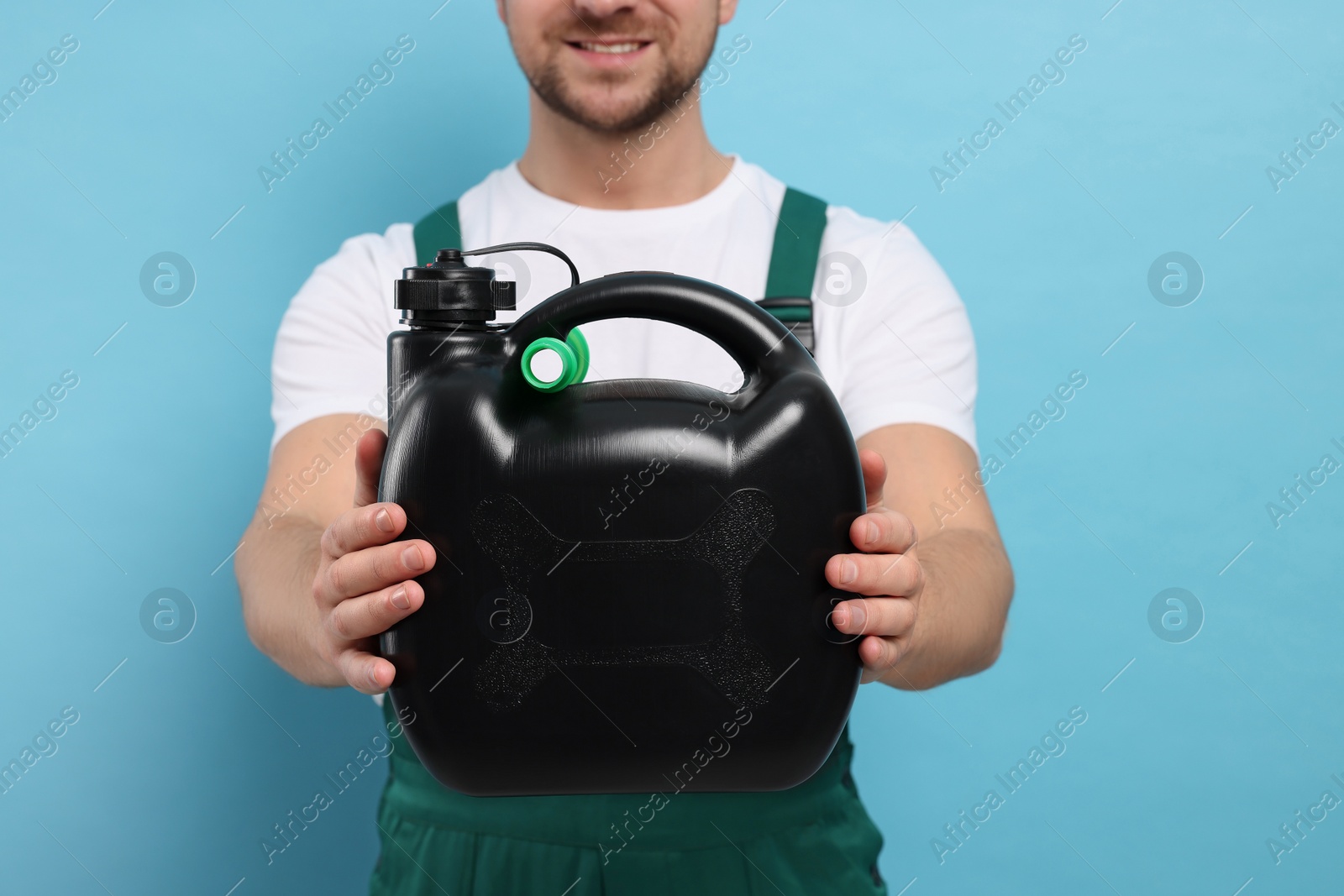 Photo of Man holding black canister on light blue background, closeup