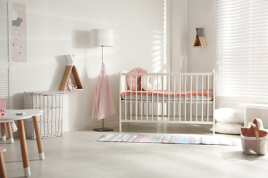 Photo of Cute baby room interior with crib and decor elements