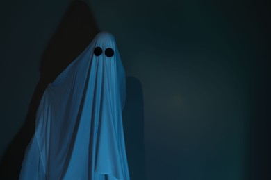 Photo of Creepy ghost. Woman covered with sheet in color light, space for text