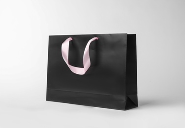 Photo of Paper shopping bag with ribbon handles on white background. Mockup for design