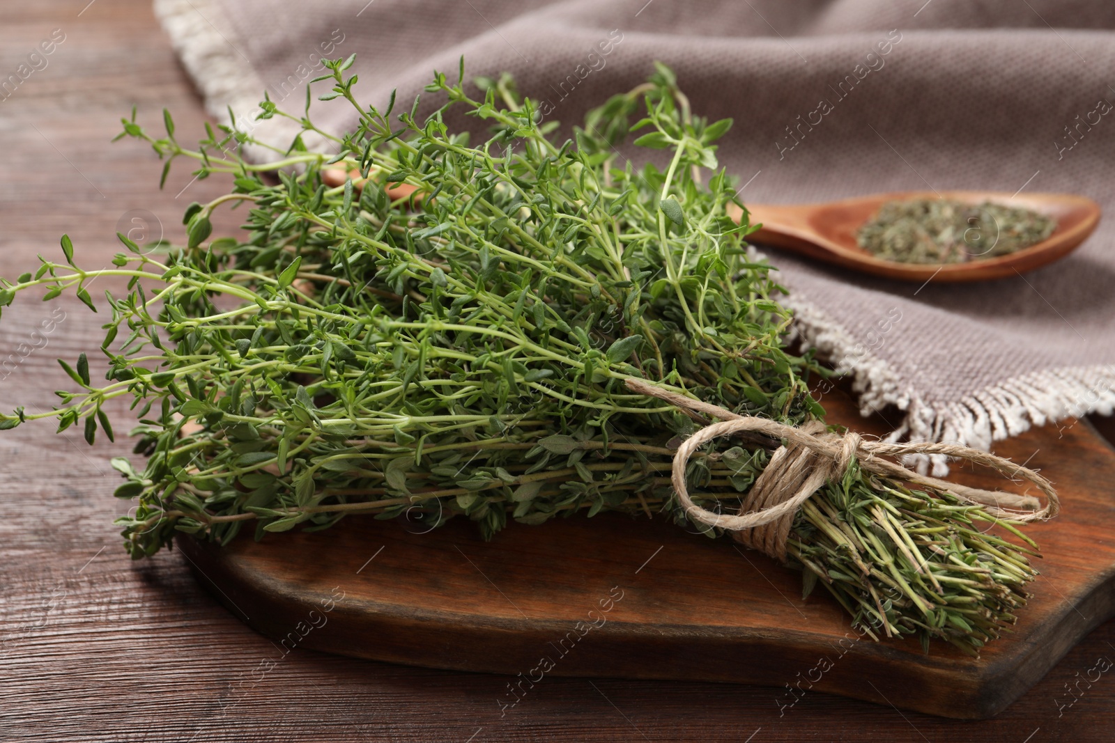 Photo of Bunch of aromatic thyme on wooden table, closeup