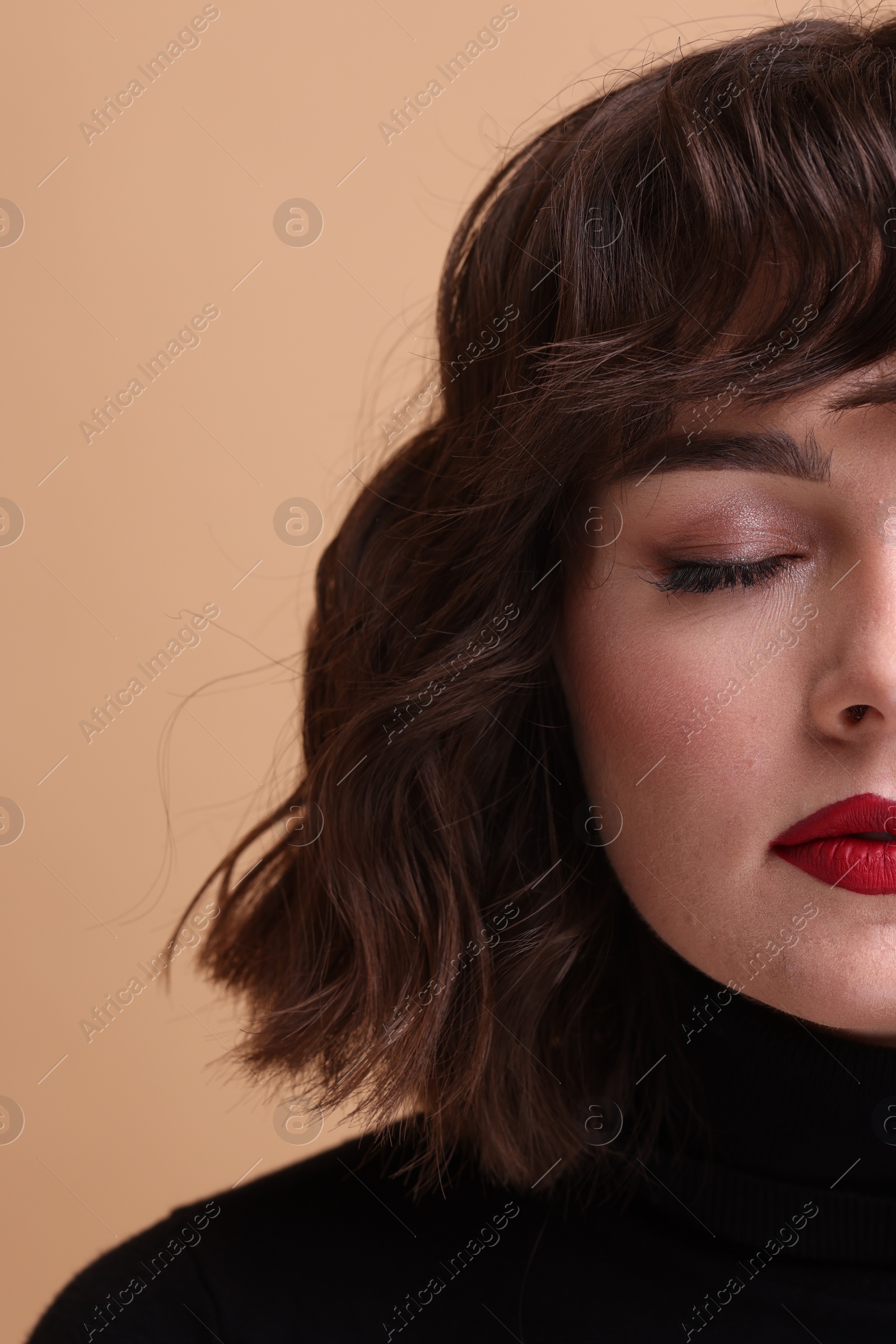 Photo of Beautiful young woman with wavy hairstyle on beige background, closeup