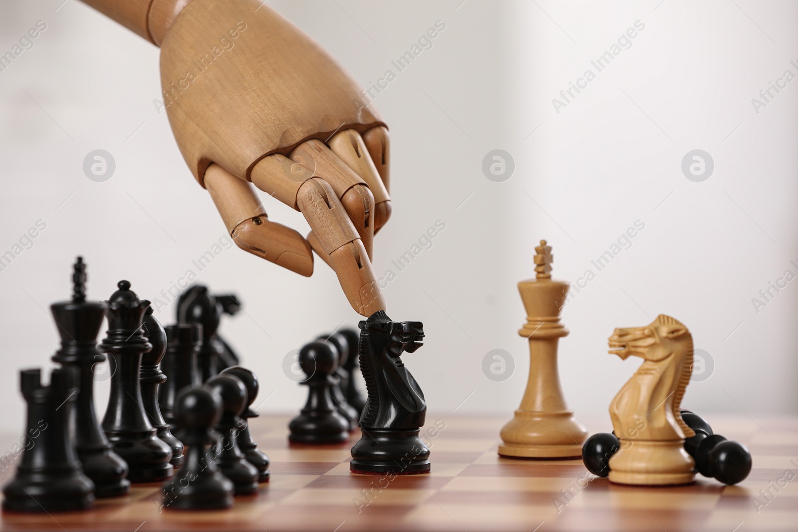 Photo of Robot moving chess piece on board against light background, closeup. Wooden hand representing artificial intelligence