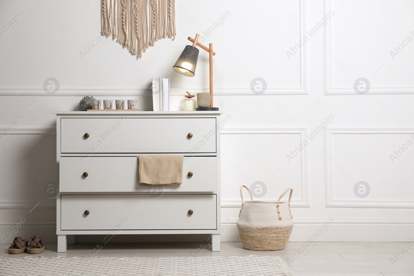 Photo of Stylish room interior with chest of drawers near white wall