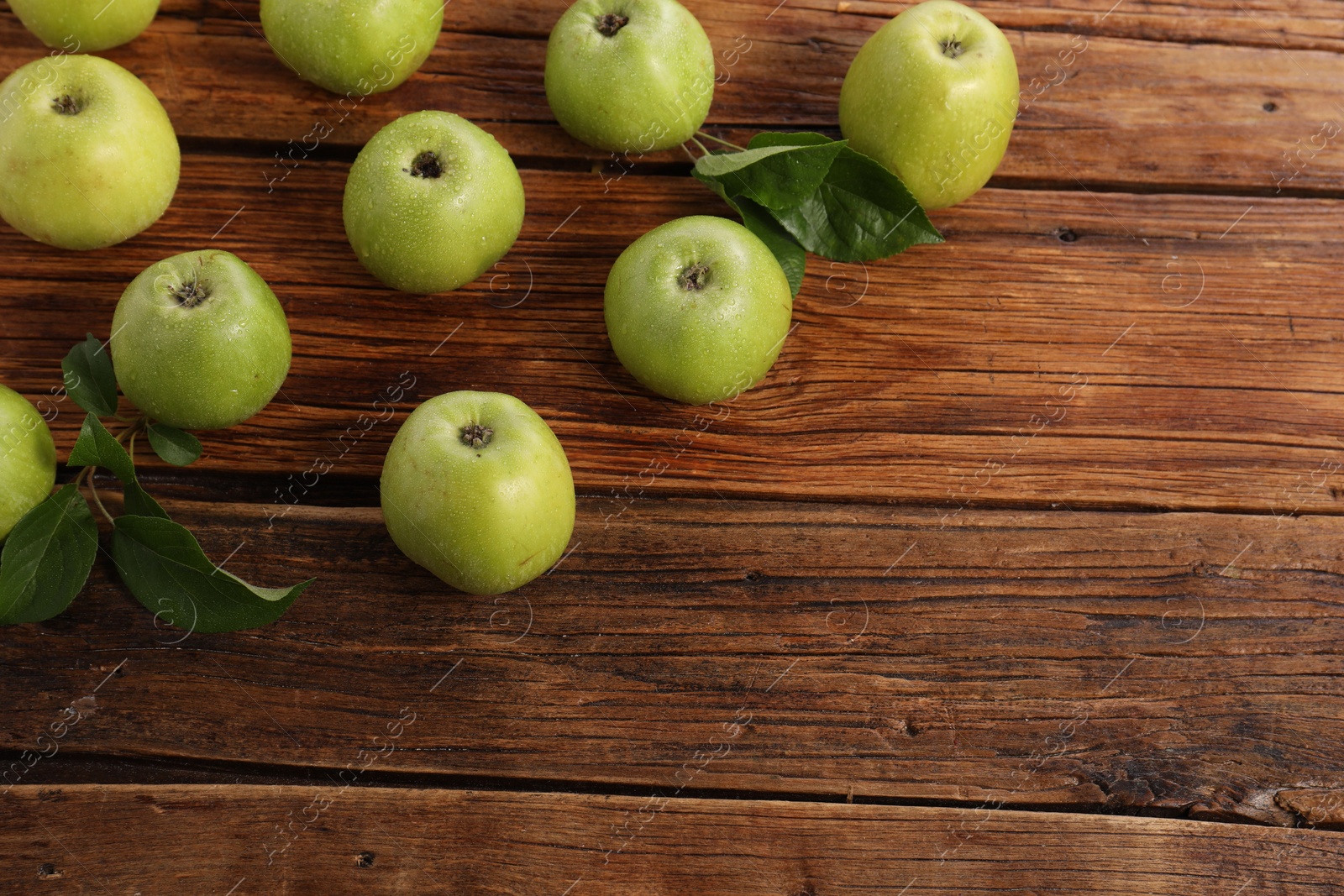 Photo of Fresh ripe green apples with water drops on wooden table. Space for text