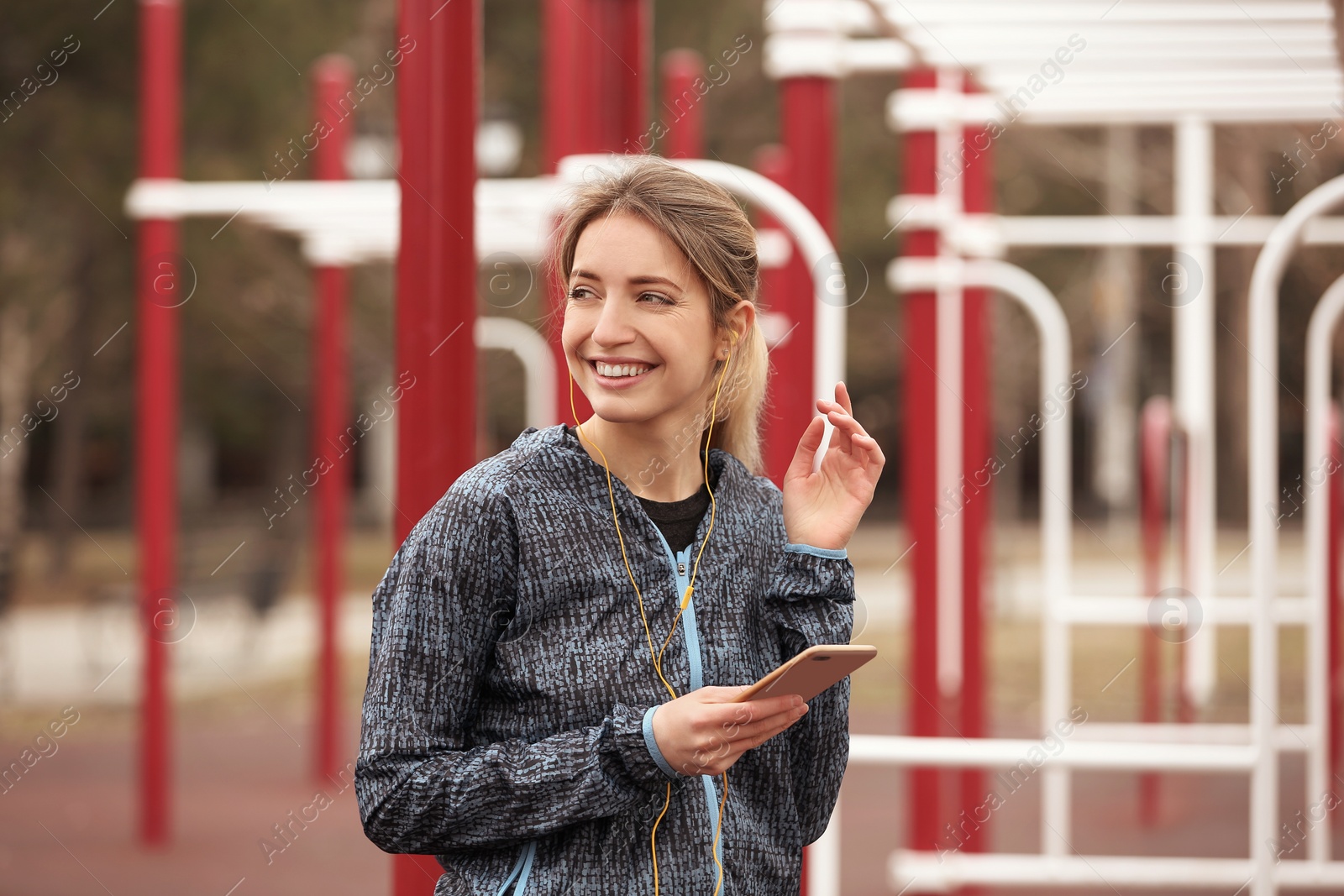 Photo of Young woman with headphones listening to music on sports ground