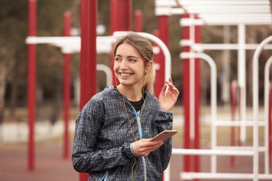 Photo of Young woman with headphones listening to music on sports ground