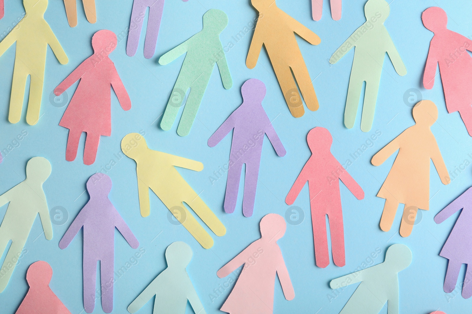 Photo of Many different paper human figures on light blue background, flat lay. Diversity and inclusion concept