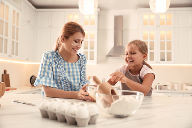 Photo of Mother and daughter making dough together in kitchen