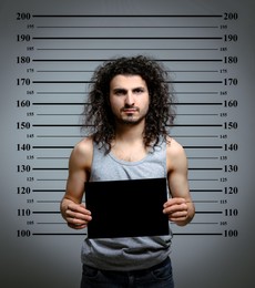 Image of Criminal mugshot. Arrested man with blank card against height chart