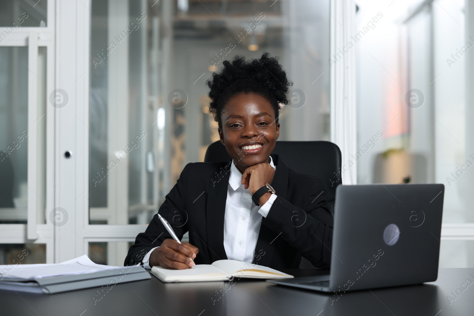 Photo of Happy woman working at table in office. Lawyer, businesswoman, accountant or manager