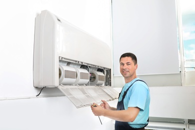 Photo of Technician installing and checking air conditioner indoors