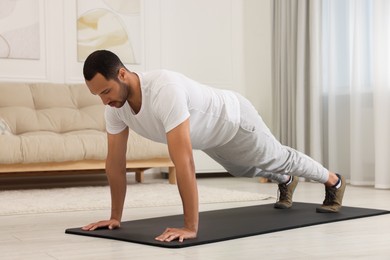 Man doing morning exercise on fitness mat at home