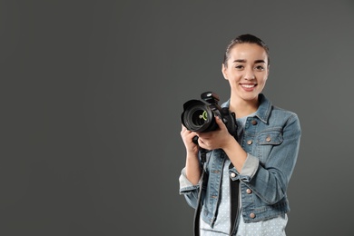 Photo of Young woman with camera and space for text on gray background. Professional photo studio