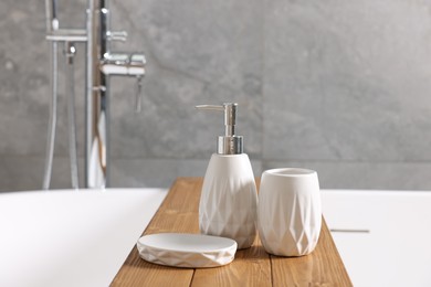 Photo of Set of bath accessories on tub in bathroom