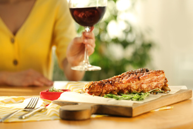 Photo of Woman having lunch in restaurant, focus on delicious roasted ribs