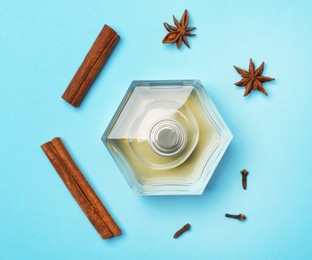 Bottle of perfume and spices on color background, top view