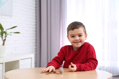 Cute little boy with coins at home. Counting money
