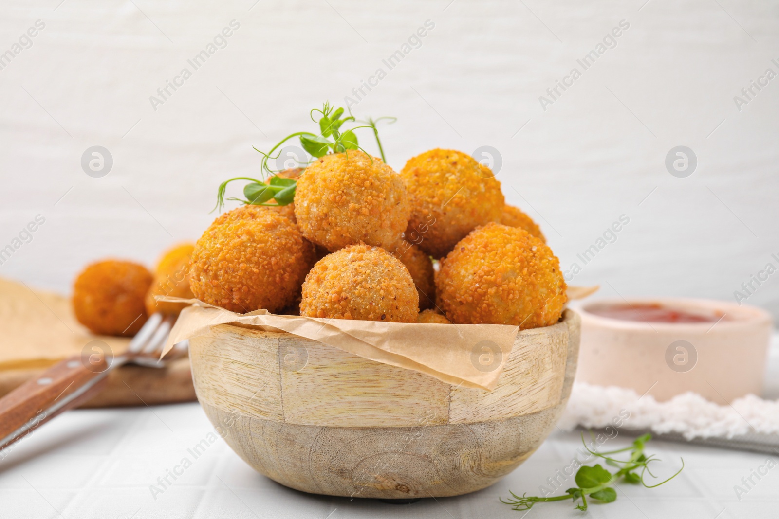 Photo of Bowl of delicious fried tofu balls with pea sprouts on white tiled table