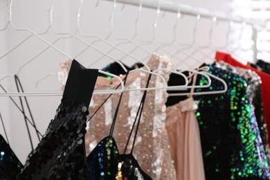 Stylish party dresses on rack indoors, closeup