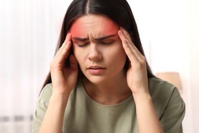 Young woman suffering from headache at home