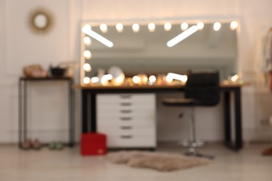 Blurred view of makeup room with stylish mirror, dressing table and chair