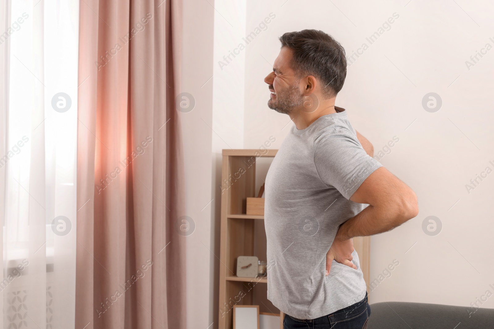 Photo of Man suffering from back pain indoors. Space for text