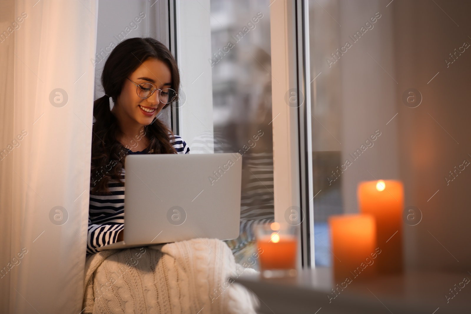 Photo of Young woman using laptop near window at home. Winter atmosphere