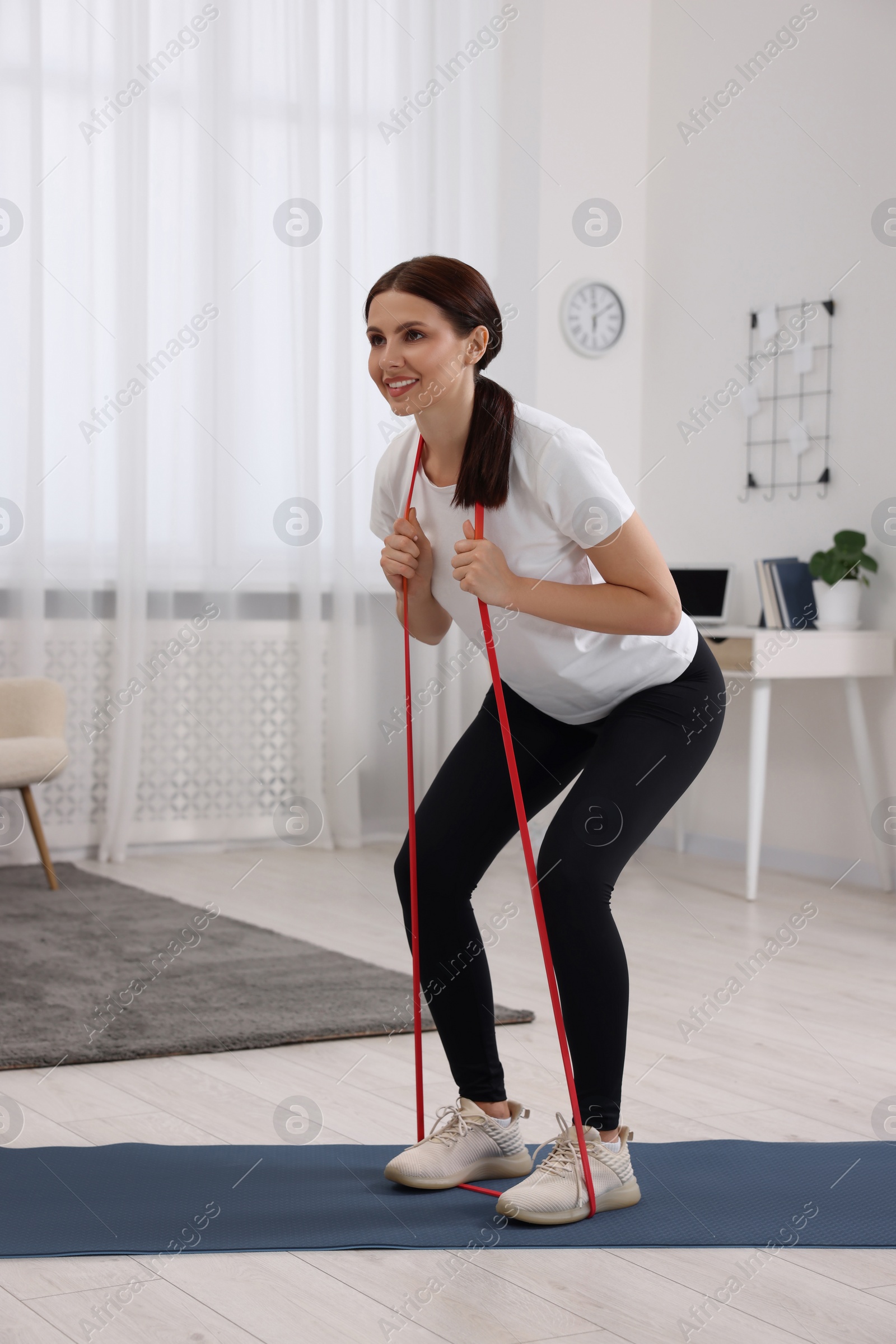 Photo of Happy woman doing morning exercise with stretching band at home