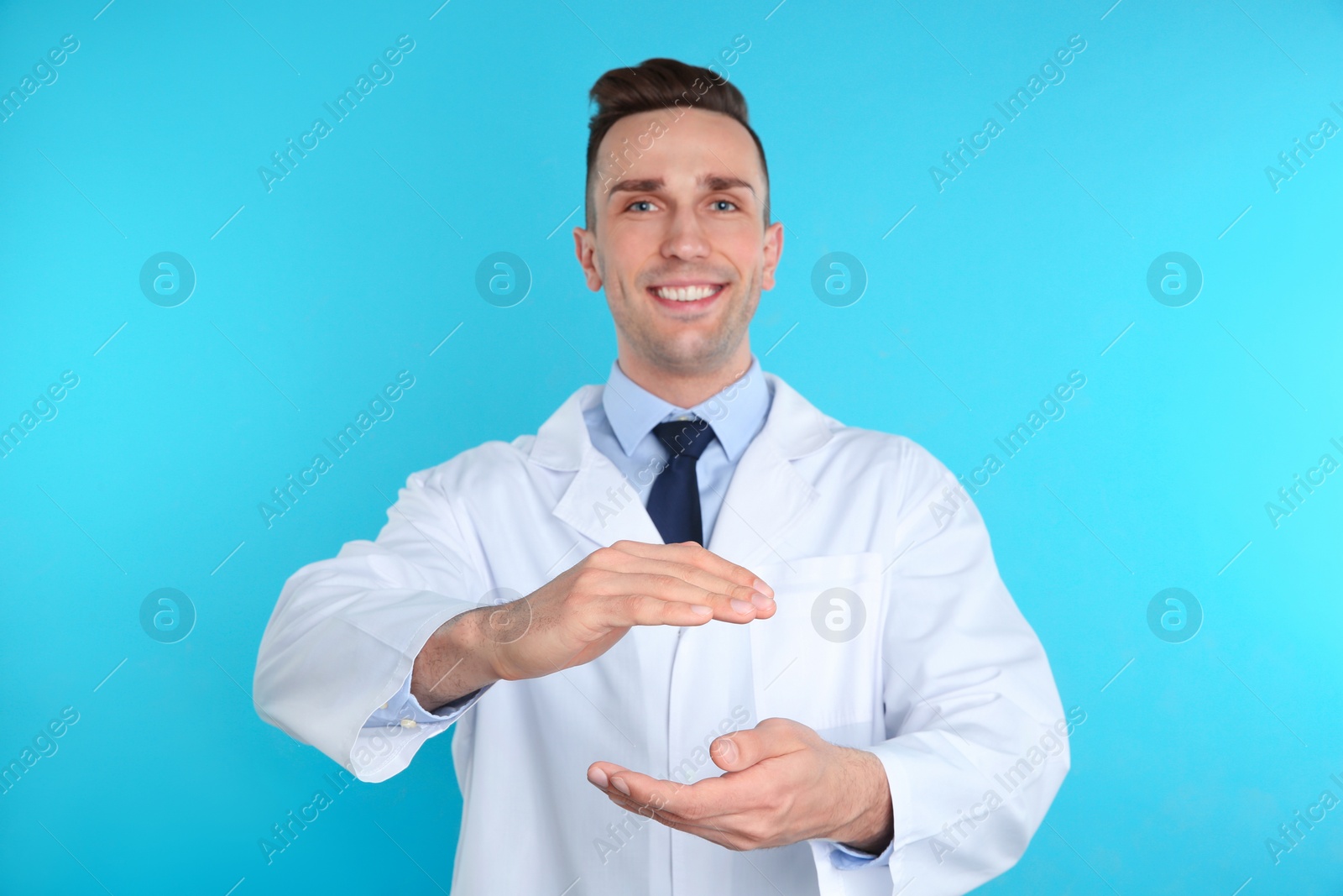 Photo of Male dentist holding something on color background