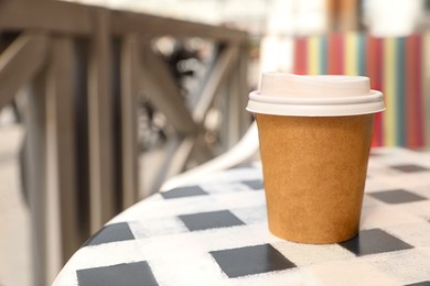 Photo of Takeaway paper cup with hot coffee on table outdoors, space for text