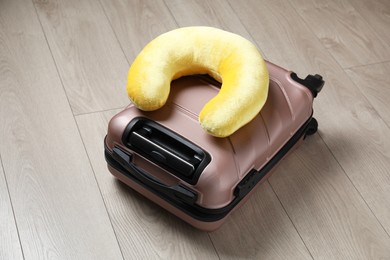 Photo of Yellow travel pillow and suitcase on floor