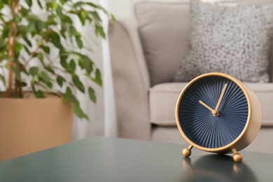 Photo of Stylish analog clock on table in living room, space for text. Time of day
