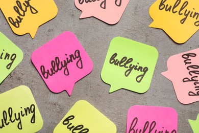Notes with word Bullying on grey table, flat lay