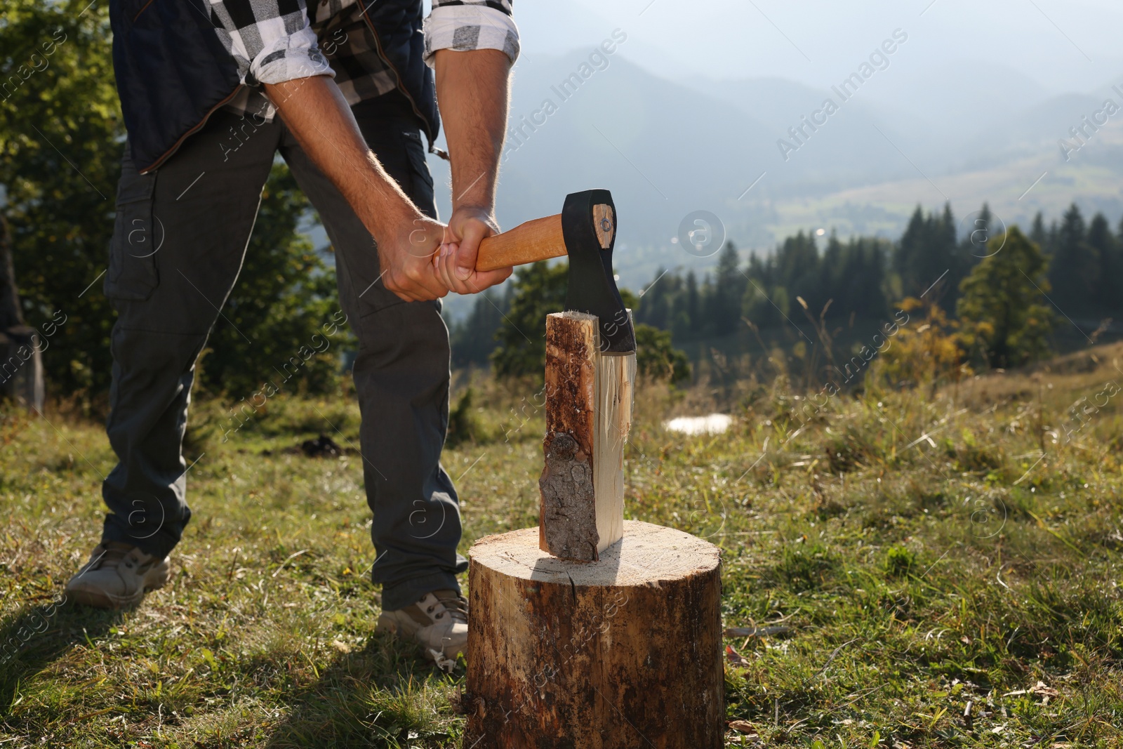 Photo of Man with axe cutting firewood in mountains, closeup