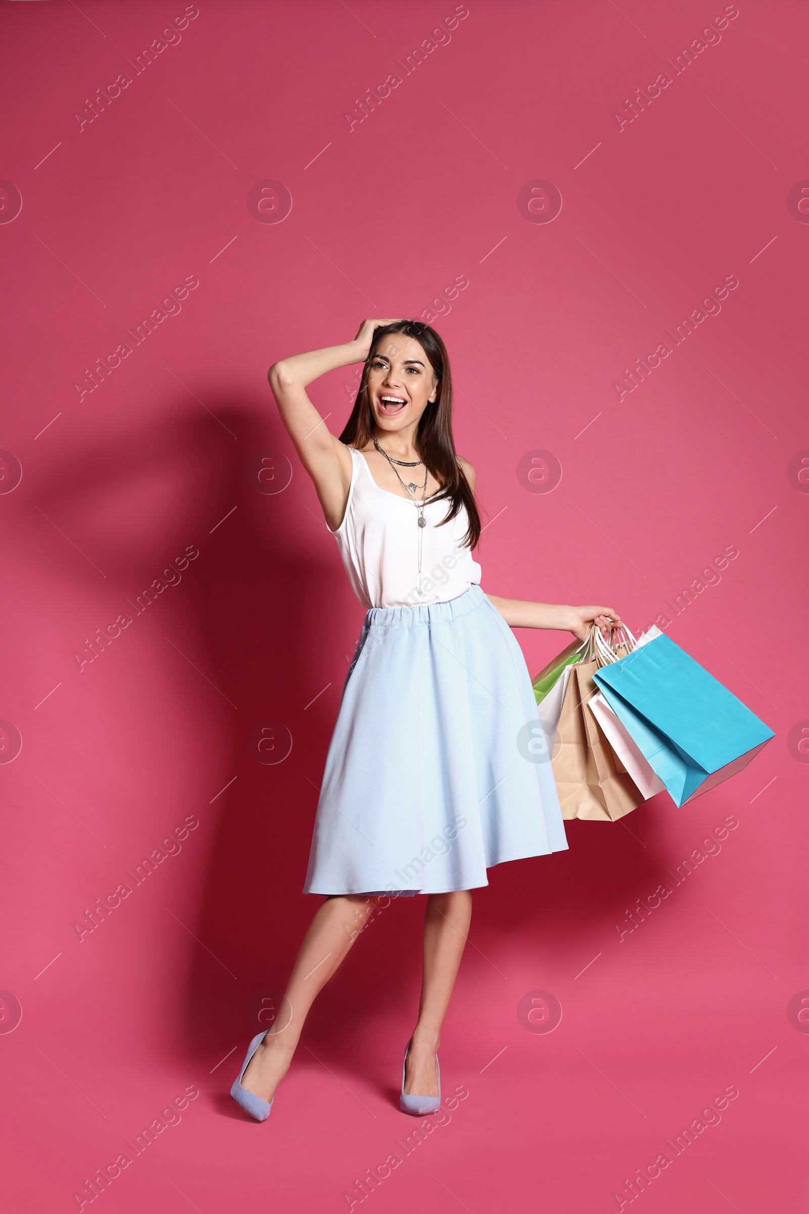 Photo of Young woman with shopping bags on color background