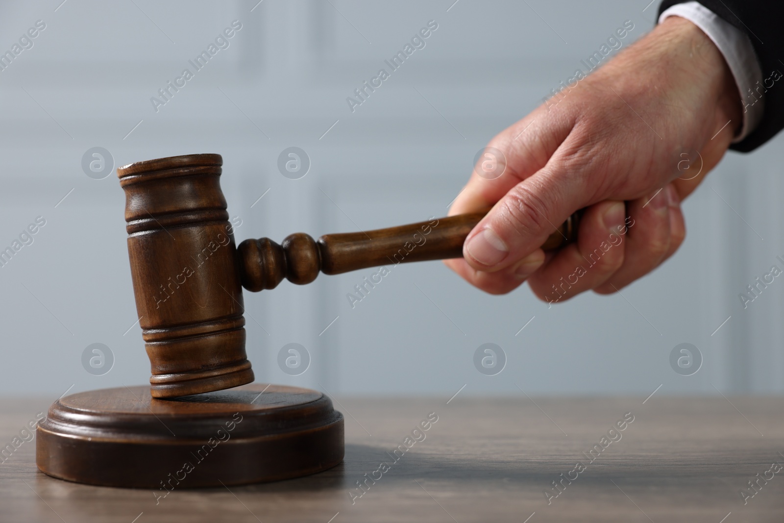 Photo of Judge with gavel at wooden table indoors, closeup
