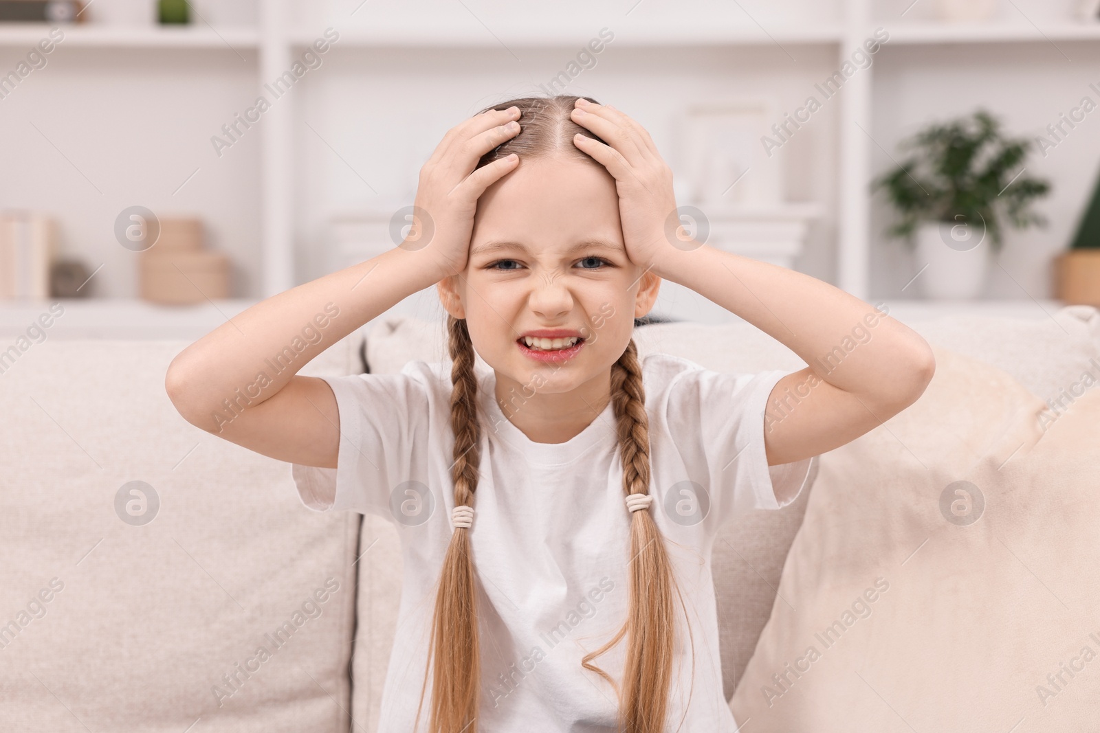 Photo of Little girl suffering from headache at home