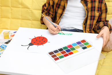 Photo of Little child painting on sofa at home, closeup