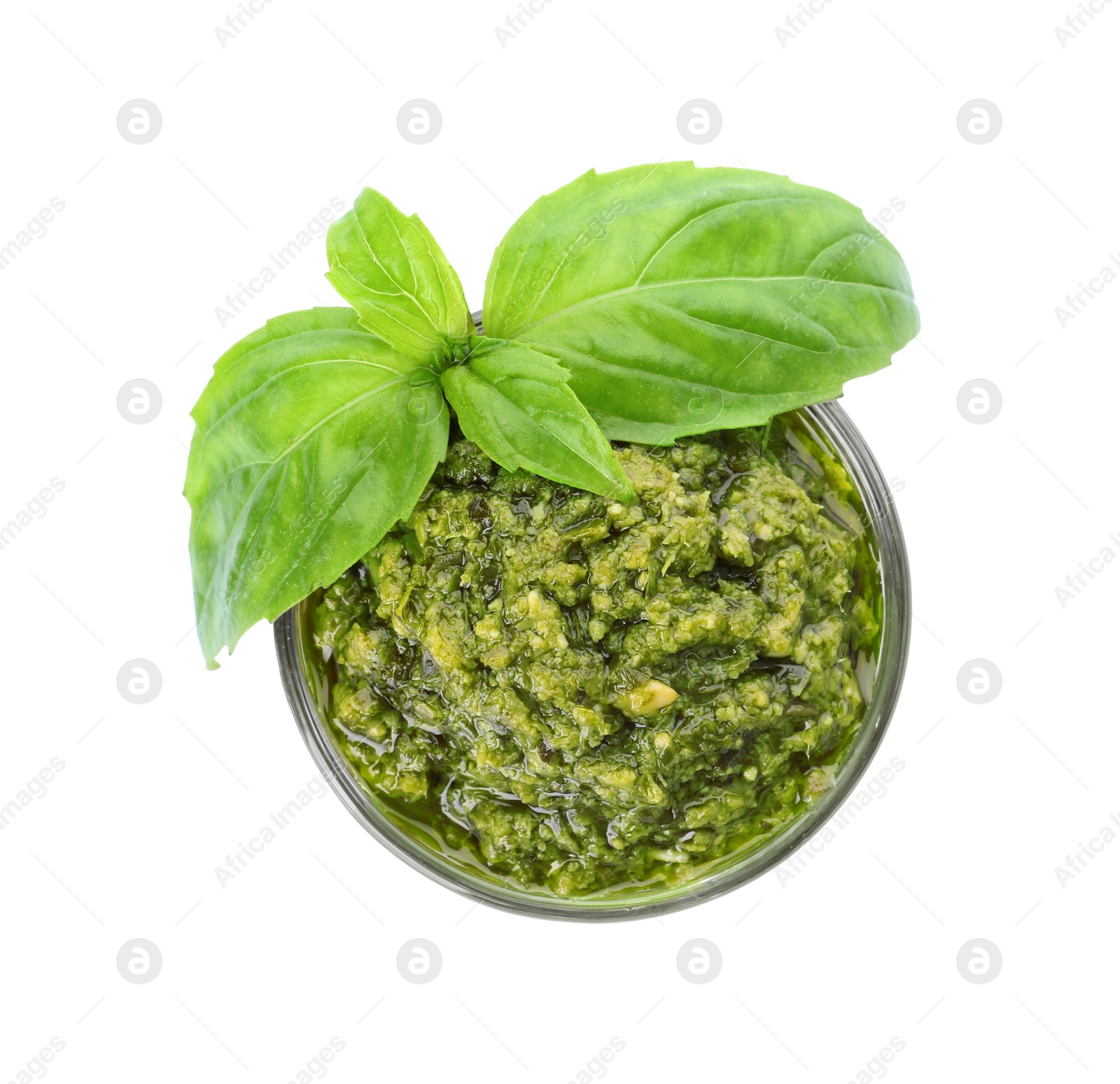 Photo of Bowl of tasty pesto sauce with basil leaves isolated on white, top view