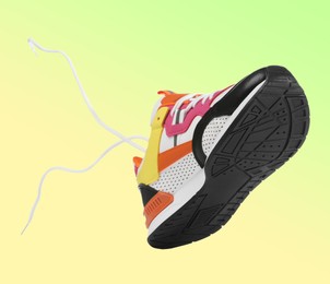 Image of One stylish sneaker in air on color gradient background